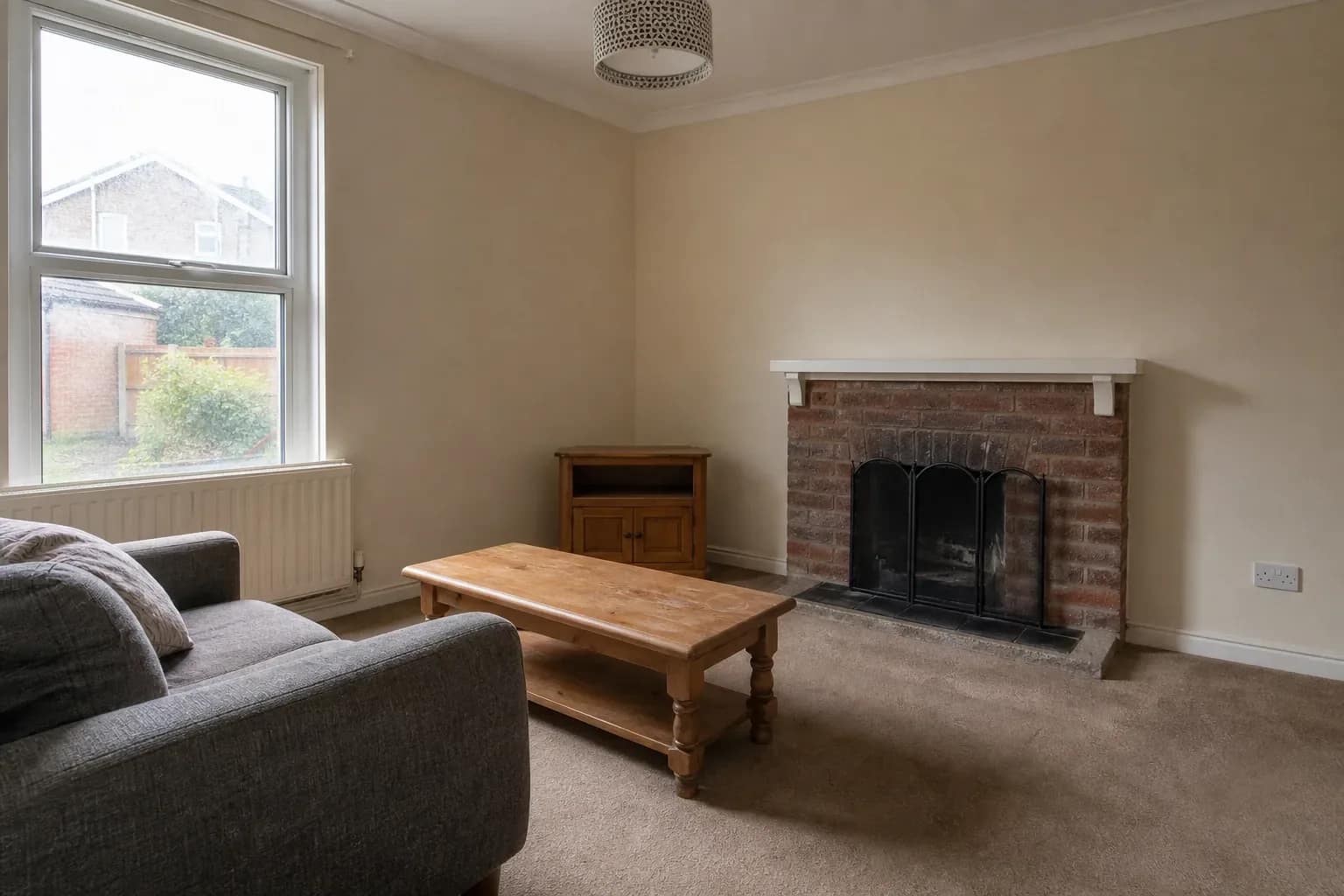Living room with a plain sofa and fireplace photographed from a corner in daylight