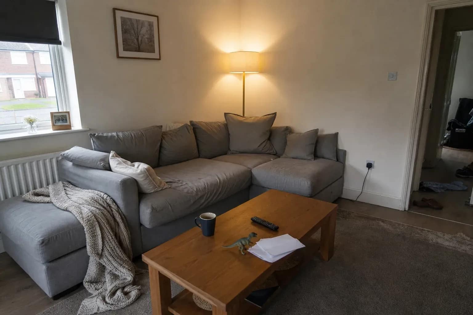A lived-in family living room with a sectional sofa, scattered toys and opened mail on the coffee table