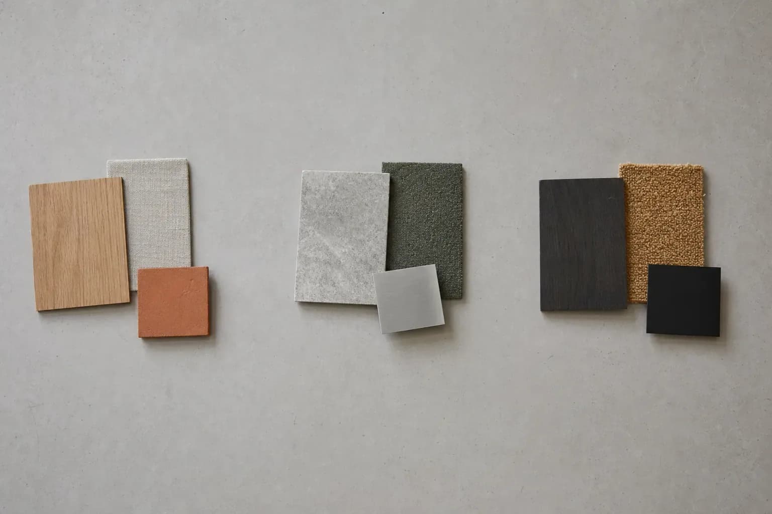 Three separate groups of material samples arranged in clusters on a pale worktop
