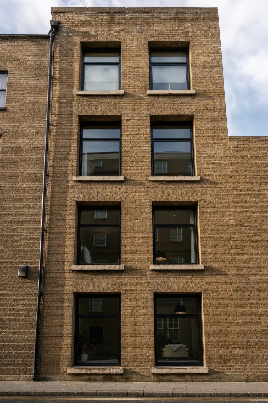 Narrow brick facade with deeply recessed windows and slim metal mullions seen from street level