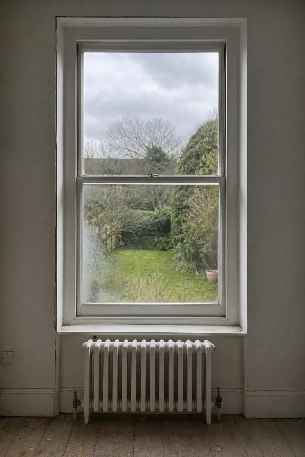 Tall timber sash window with a deep plaster reveal and a painted radiator directly beneath it