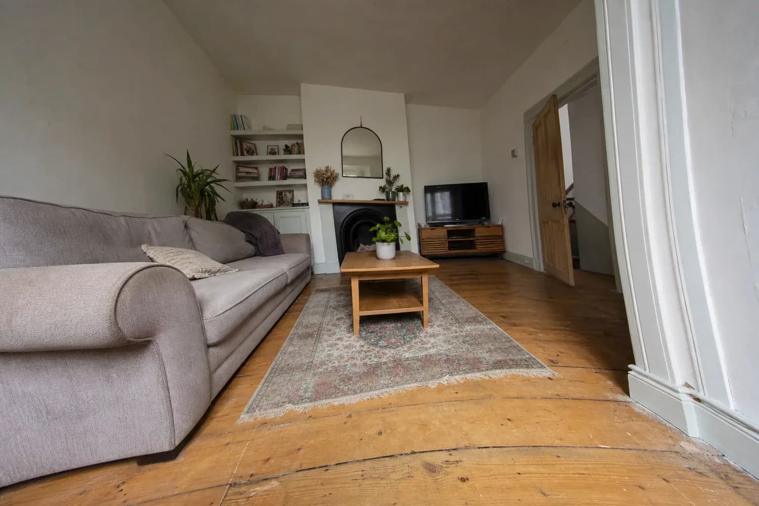 Living room shot very wide, sofa arm stretched at the frame edge and the door casing bowed outward