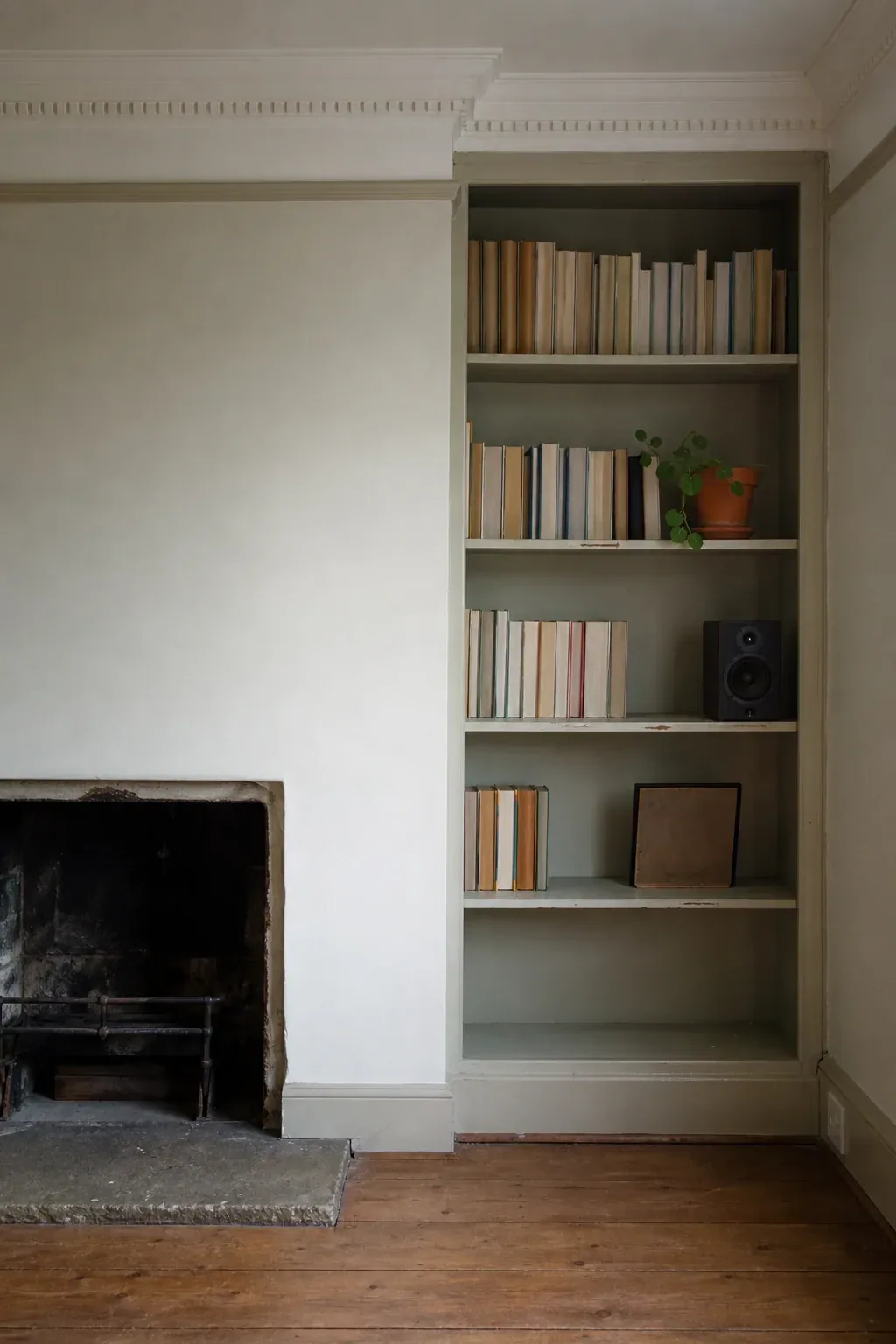 Painted built-in shelving filling the recess beside a plain fireplace in an older living room