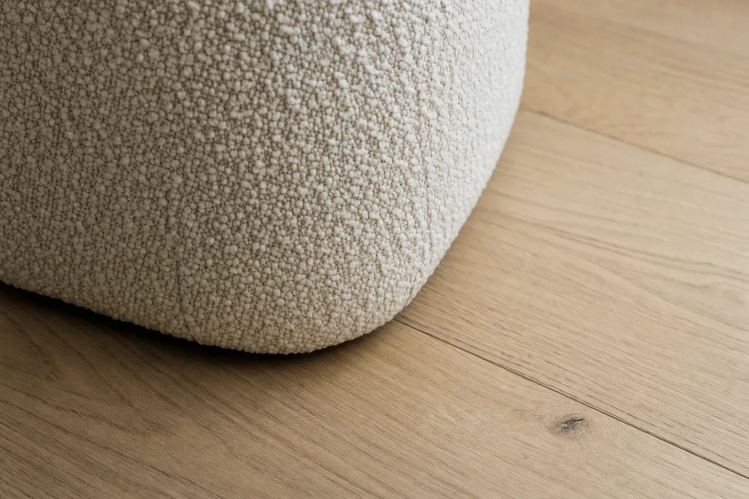 Macro detail of bouclé weave meeting an oak floor in a finished render